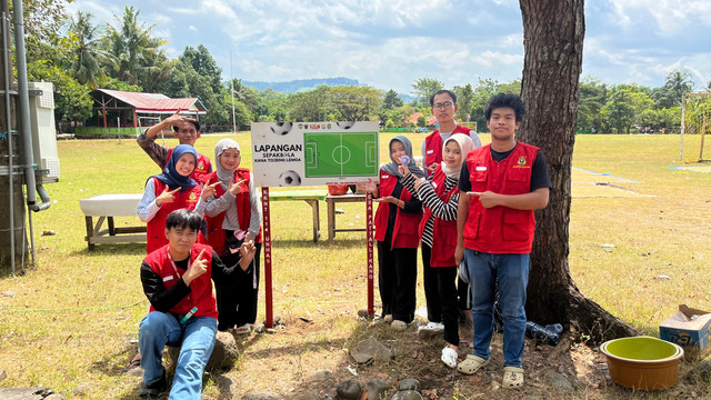 Mahasiswa KKN Universitas Hasanuddin Desa Pattallikang dan Papan Nama Lapangan Kana Tojeng Lemoa 