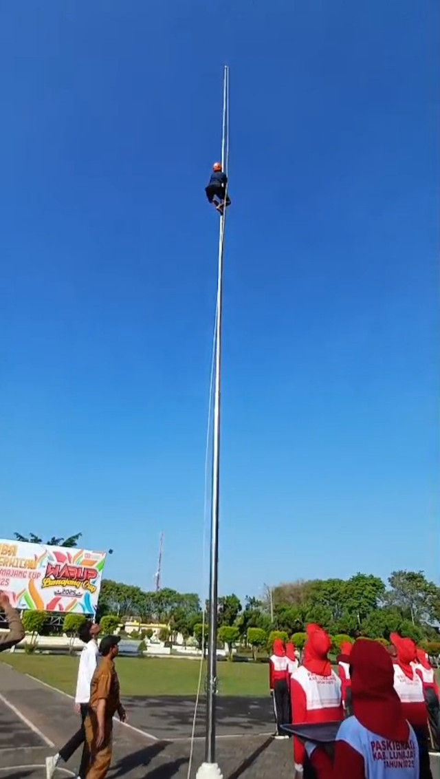 Sulasmono Mahmud saat memanjat tiang untuk mengambil tali bendera yang nyangkut di Alun-Alun Kabupaten Lumajang. Foto: Dok. Istimewa