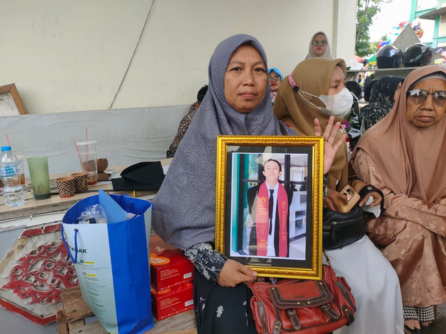 Ibunda Rio, Sri Aziza saat memegang foto almarhum anaknya saat wisuda di IAIN Pontianak. Foto: Istimewa.