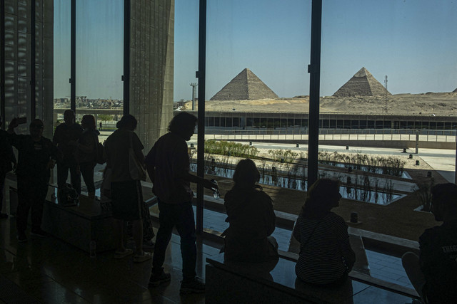 Pengunjung memandang ke arah kompleks Piramida Giza saat mereka mengunjungi Museum Mesir Besar di Giza, Khario, Mesir, Senin (5/5/2025). Foto: Khaled Desouki/AFP