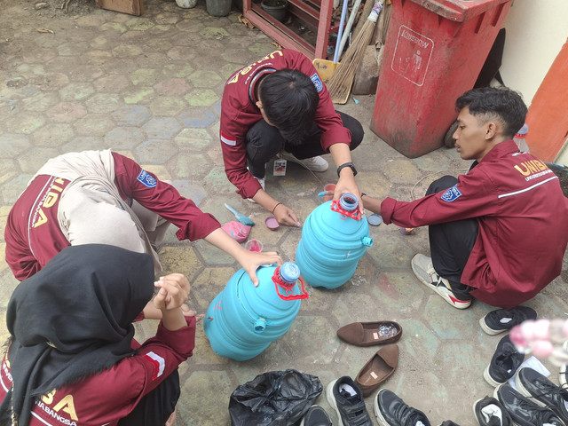 Tim KKM menyiapkan galon dan bahan cat sebelum diserahkan kepada siswa.