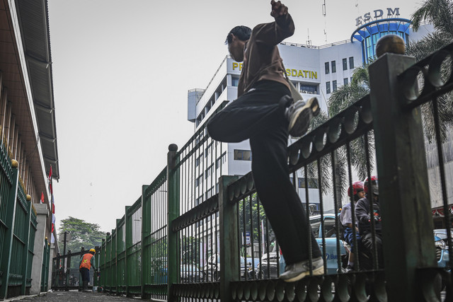 Warga melompati pagar saat berlangsungnya proyek peninggian pagar di Stasiun Cikini, Jakarta, Senin (11/8/2025). Foto: Sulthony Hasanuddin/ANTARA FOTO 