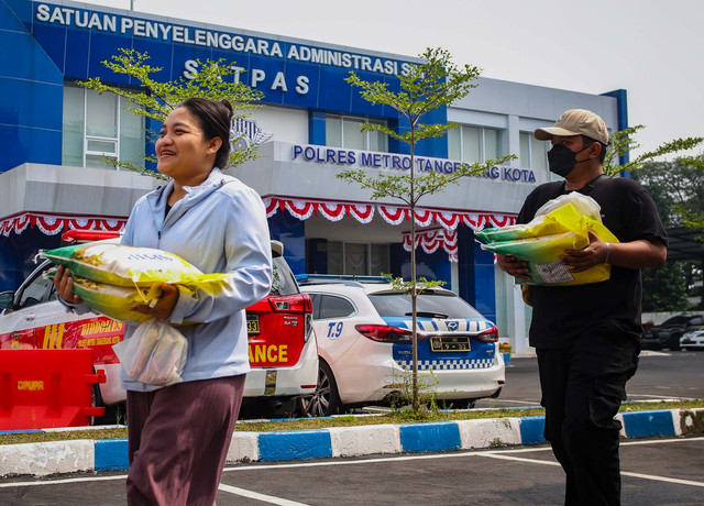 Warga pemohon urat ijin mengemudi (SIM) membawa beras medium SPHP yang dibeli saat Gerakan Pangan Murah (GPM) Polri dan cek kesehatan gratis halaman Satuan Penyelenggara Administrasi (Satpas) SIM Polres Metro Tangerang Kota, Tangerang, Rabu (13/8). Foto: Muhammad Iqbal/ANTARA FOTO