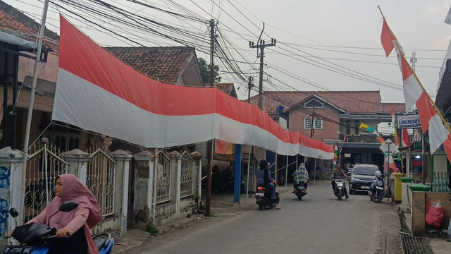 Warga melintasi bendera sepanjang 680 meter yang dipasang oleh Rosadi, kuli bangunan di Cianjur. Foto: Dok. kumparan