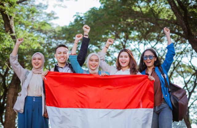Pemuda mengibarkan bendera Merah Putih dengan penuh semangat dalam perayaan Hari Kemerdekaan. Sumber Gambar: Freepik