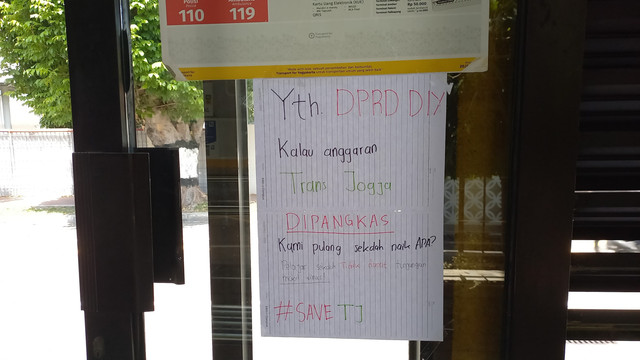 Sebuah tulisan protes muncul di halte Trans Jogja di Jalan Kenari, Kota Yogyakarta bertuliskan "Yth DPRD DIY Kalau Anggaran Trans Jogja Dipangkas Kami Pulang Sekolah Naik Apa?".  Foto: Arfiansyah Panji/kumparan