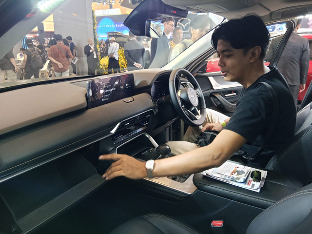 Seorang pengunjung GIIAS Surabaya 2025 sedang mencoba mobil mewah yang dipamerkan. Foto: Masruroh/Basra