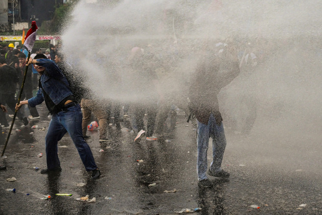 Polisi menembakkan waten canon ke arah massa saat demo ricuh di depan Gedung DPR/MPR, Jakarta, Kamis (28/8/2025). Foto: Bay Ismoyo/AFP