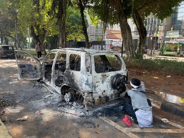 Pengunjuk rasa mengambil sisa-sisa besi dari mobil yang hangus terbakar saat aksi di kawasan Mako Brimob Kwitang, Jakarta, Jumat (29/8/2025).  Foto: Darryl Ramadhan/kumparan