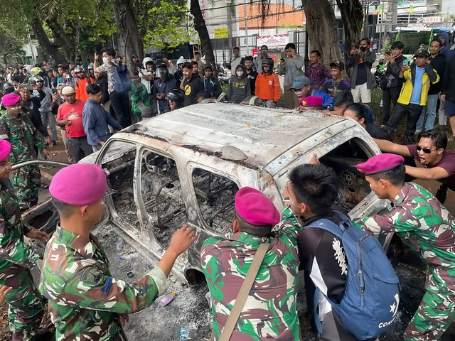 Sejumlah petugas TNI bersama massa aksi dan warga mengevakuasi kendaraan yang hangus terbakar saat aksi di kawasan Mako Brimob Kwitang, Jakarta, Jumat (29/8/2025). Foto: Darryl Ramadhan/kumparan