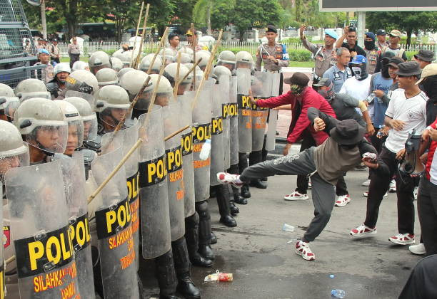 Polisi anti huru hara menahan serangan massa. Foto: Istock/Didindan Bintang