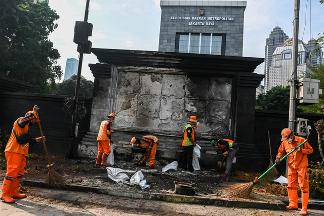 Petugas membersihkan puing-puing sisa kerusuhan di depan Polda Metro Jaya, Jakarta, Minggu (31/8/2025). Foto: Sulthony Hasanuddin/ANTARA FOTO 