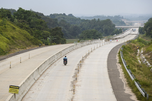 Warga menggunakan motor melintas di kawasan pembangunan tol Serang-Panimbang seksi II di Cikulur, Lebak, Banten, Sabtu (6/9/2025). Foto: Muhammad Bagus Khoirunas/ANTARA FOTO
