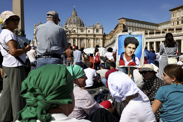 Seorang pria memegang sebuah karya seni pada hari Paus Leo XIV memimpin Misa Kudus untuk kanonisasi Carlo Acutis yang ditahbiskan sebagai orang suci Katolik, dan Pier Giorgio Frassati di Lapangan Santo Petrus di Vatikan, Minggu (7/9/2025). Foto: Matteo Minnella/Pool/REUTERS
