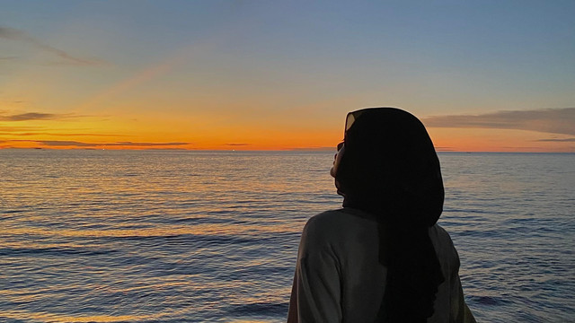 Potret siluet di tepi laut saat matahari tenggelam, merepresentasikan kehangatan sore dalam film Sore: Istri dari Masa Depan (dokumentasi pribadi penulis)