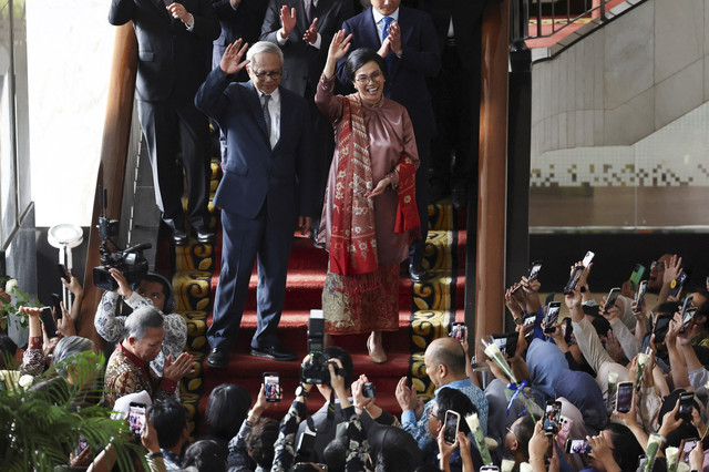 Menteri Keuangan Indonesia yang akan keluar Sri Mulyani Indrawati, didampingi suaminya Tonny Sumartono, melambai kepada staf Kementerian Keuangan, usai upacara serah terima di Jakarta, Selasa (9/9/2025). Foto: Willy Kurniawan/REUTERS