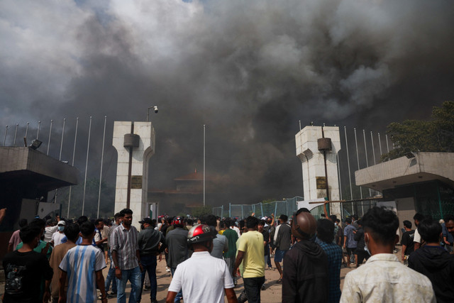 Demonstran berkumpul saat asap mengepul di kompleks Parlemen, Kathmandu, Nepal, Selasa (9/9/2025). Foto: Adnan Abidi/REUTERS