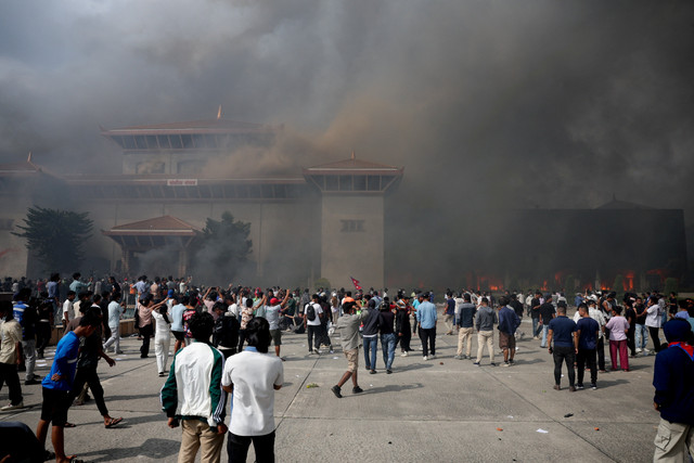 Demonstran berkumpul saat asap mengepul di kompleks Parlemen, Kathmandu, Nepal, Selasa (9/9/2025). Foto: Adnan Abidi/REUTERS
