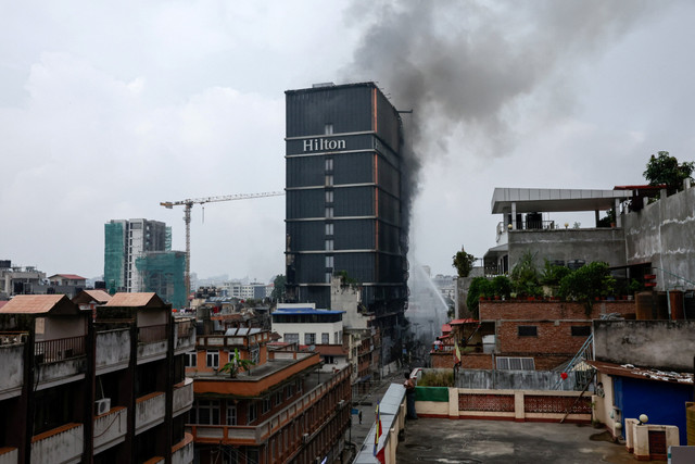 Asap mengepul dari Hotel Hilton Kathmandu yang terbakar menyusul protes berujung ricuh di Kathmandu, Nepal, Rabu (10/9/2025), Foto: Shutterstock
