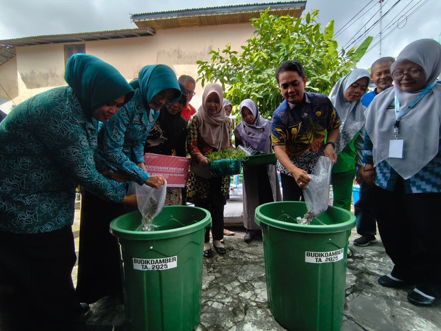 Wakil Wali Kota Pontianak Bahasan bersama Ketua TP PKK Kota Pontianak Yanieta Arbiastutie Kamtono, memasukkan bibit ikan lele ke dalam ember untuk budidaya. Foto: Dok. Prokopim Pemkot Pontianak 