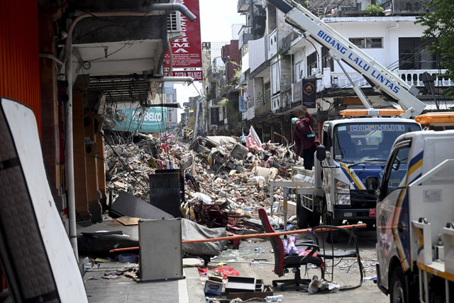 Sejumlah warga membersihkan puing-puing pascabanjir di Denpasar, Bali, Jumat (12/9/2025). Foto: Sonny Tumbelaka/AFP