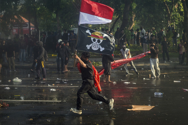 Demonstran membawa bendera one piece saat aksi menuntut pengusutan kasus penabrakan pengemudi ojek daring Affan Kurniawan oleh mobil rantis Brimob di depan kantor Gubernur Surabaya, Jawa Timur, Jumat (29/8/2025). Foto: Juni Kriswanto/AFP