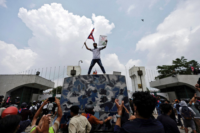 Seorang demonstran mengibarkan bendera sambil berdiri di atas kendaraan saat protes menentang korupsi dan keputusan pemerintah untuk memblokir beberapa platform media sosial di Kathmandu, Nepal, Senin (8/9/2025). Foto: Navesh Chitrakar/REUTERS