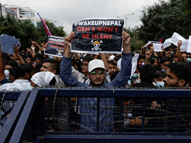 Para demonstran membawa plakat di balik barikade selama protes menentang korupsi dan keputusan pemerintah untuk memblokir beberapa platform media sosial di Kathmandu. Sumber: Kumparan.com 