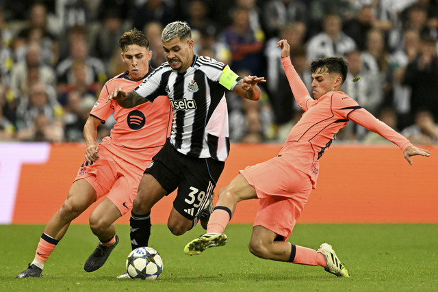 Pemain Newcastle United Bruno Guimaraes berusaha melewati dua pemain FC Barcelona pada pertandingan Liga Champions Eropa di St James' Park, Newcastle, Inggris, Kamis (18/9/2025). Foto: Oli Scarff/AFP