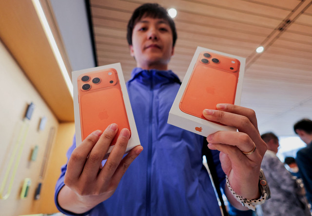 Seorang pria menunjukkan kotak-kotak berisi ponsel pintar seri iPhone 17 yang baru dibeli di dalam toko Apple di kawasan Sanlitun, Beijing, saat dimulainya penjualan di Beijing, China, Jumat (19/9/2025). Foto: Maxim Shemetov/REUTERS