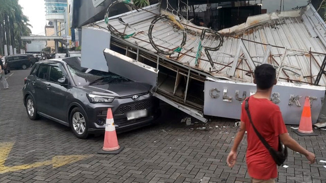 Kondisi mobil pribadi milik anggota Polri di Manado yang rusak tertimpa kanopi dan papan nama eks klub malam di kawasan Bahu Mall Manado, Jumat, 19 September 2025. (foto: febry kodongan)
