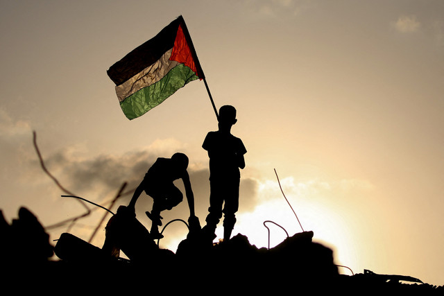 Seorang anak mengibarkan bendera Palestina di atas reuntuhan bangunan di kamp pengungsi Bureij, Jalur Gaza tengah, Senin (22/9/2025). Foto: Eyad BABA / AFP