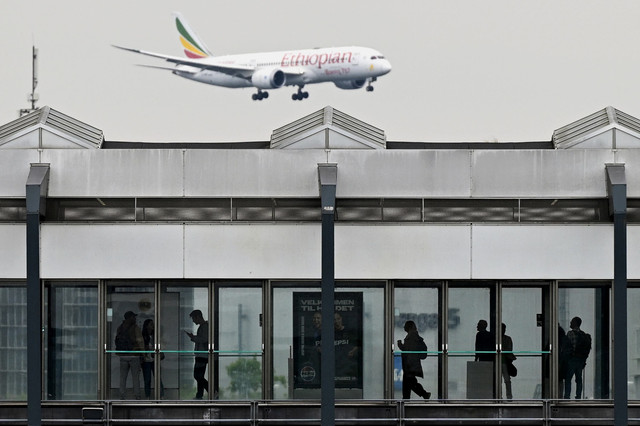 Orang-orang menunggu kereta di stasiun metro saat pesawat penumpang Boeing 787-8 Ethiopian Airlines terbang di langit saat mendarat di Bandara Kopenhagen, Denmark, Rabu (4/9/2025). Foto: Sergei Gapon/AFP