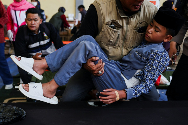 Seorang siswa digotong untuk melakukan perawatan usai keracunan Makan Bergizi Gratis (MBG) di Bandung, Jawa Barat. Foto: Willy Kurniawan/REUTERS