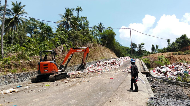 Petugas dari Dinas Lingkungan Hidup (DLH) Kota Manado tengah membersihkan sampah yang berserakan dan telah menutupi ruas jalan di Kelurahan Kima Atas, Kecamatan Mapanget, Kamis 2 Oktober 2025. (foto: swingly manderes)