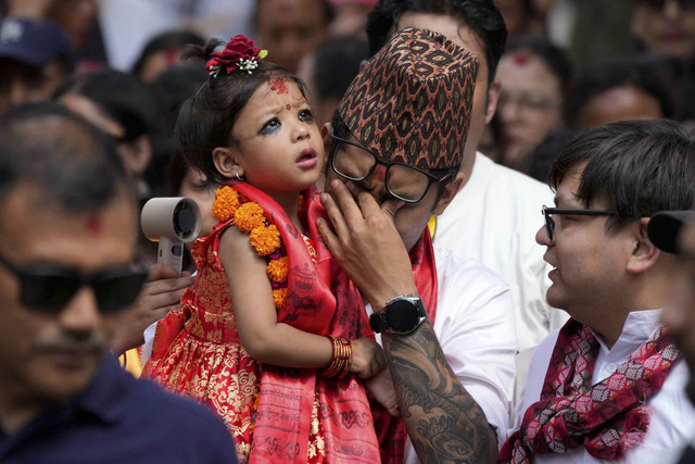 Dewi Hidup Nepal yang baru saja ditunjuk, Kumari Aryatara Shakya, dibawa oleh ayahnya saat mereka berjalan menuju Kumari Ghar, istana kuil tempat ia akan tinggal di Kathmandu, Nepal, Selasa (30/9/2025). Foto: Niranjan Shrestha/AP Photo
