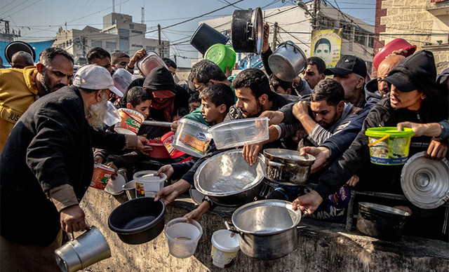 Orang-orang yang terpaksa meninggalkan rumah mereka menunggu makanan di Kamp Al-Shaboura, di pusat Rafah, Gaza, pada 17–18 Desember 2023. Kredit foto: WHO.