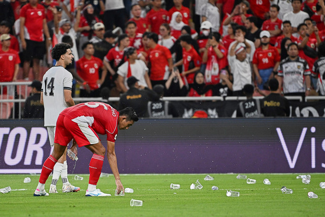 Pemain Timnas Indonesia Rizky Ridho memunguti gelas air yang dilempar suporter saat melawan Timnas Irak pada pertandingan Grup B Ronde 4 Kualifikasi Piala Dunia 2026 di King Abdullah Sports City Stadium, Jeddah, Arab Saudi, Sabtu (11/10/2025). Foto: Ali Issa/AP Photo