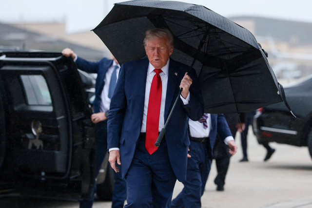 Presiden AS Donald Trump memegang payung sebelum menaiki Air Force One, saat berangkat ke Mesir di Pangkalan Gabungan Andrews, Maryland, AS, Minggu (12/10/2025).  Foto: Evelyn Hockstein/REUTERS
