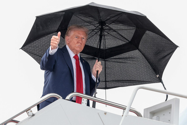 Presiden AS Donald Trump memegang payung sebelum menaiki Air Force One, saat berangkat ke Mesir di Pangkalan Gabungan Andrews, Maryland, AS, Minggu (12/10/2025).  Foto: Evelyn Hockstein/REUTERS