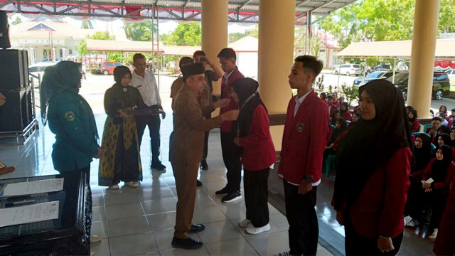 Bupati Bolmong, Yusra Alhabsyi, menyematkan tanda peserta kepada mahasiswa IKTGM yang akan mengikuti KKN Berdampak di wilayah Kabupaten Bolmong.