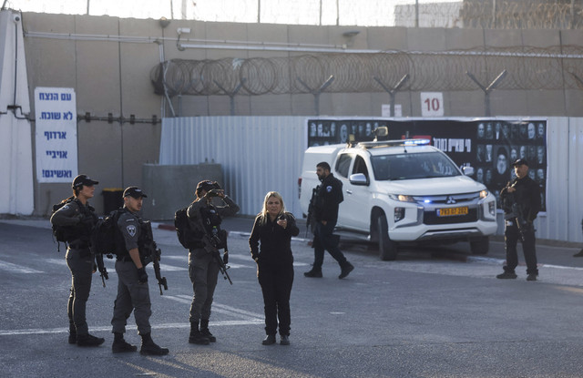 Para pejabat keamanan berdiri di luar penjara militer Israel saat pertukaran sandera-tahanan dan kesepakatan gencatan senjata di Gaza antara Hamas dan Israel, dekat Ramallah, di Tepi Barat, Senin (13/10/2025). Foto: Ammar Awad/REUTERS