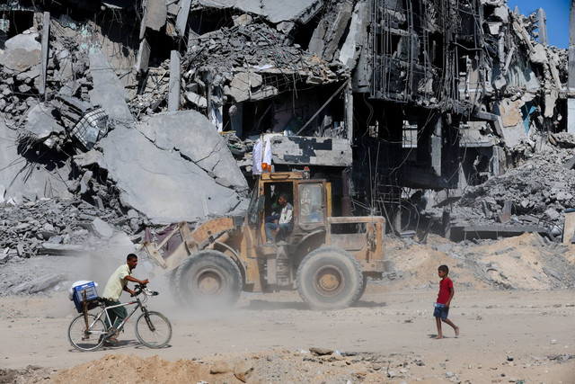 Alat berat membersihkan puing-puing bangunan yang hancur di Kota Gaza, Selasa (14/10/2025). Foto: Ebrahim Hajjaj/REUTERS