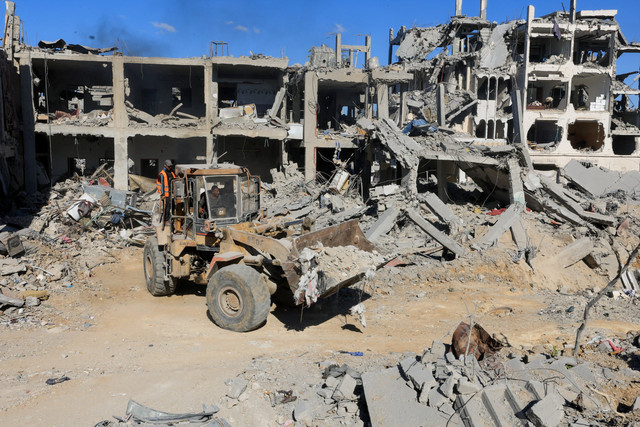 Alat berat membersihkan puing-puing bangunan yang hancur di Kota Gaza, Selasa (14/10/2025). Foto: Ebrahim Hajjaj/REUTERS