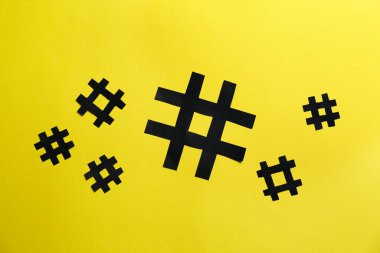 Black paper hashtag symbols on yellow background flat lay. Sumber: New Africa/Freepik