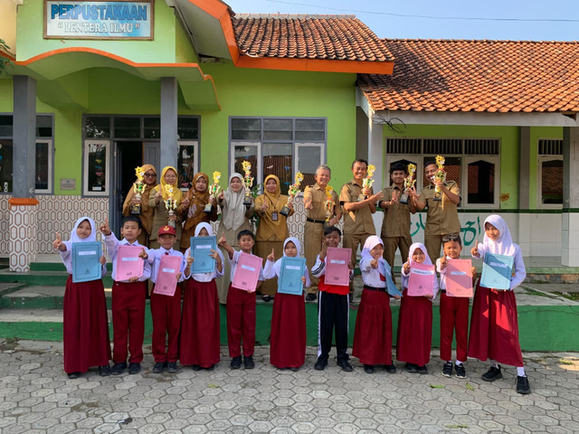 Guru dan siswa sedang berfoto bersama piala yang diraih