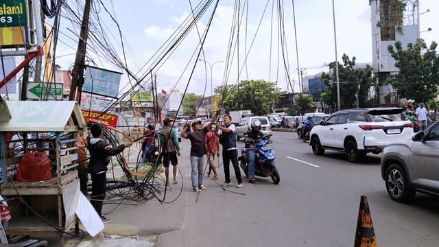 Dinas Sumber Daya Air, Bina Marga dan Bina Konstruksi (DSDABMBK) Kota Tangerang Selatan (Tangsel) mencopot tiang utilitas hampir roboh di Jalan Raya Serpong, Rabu (22/10/2025). Foto: Dok. kumparan
