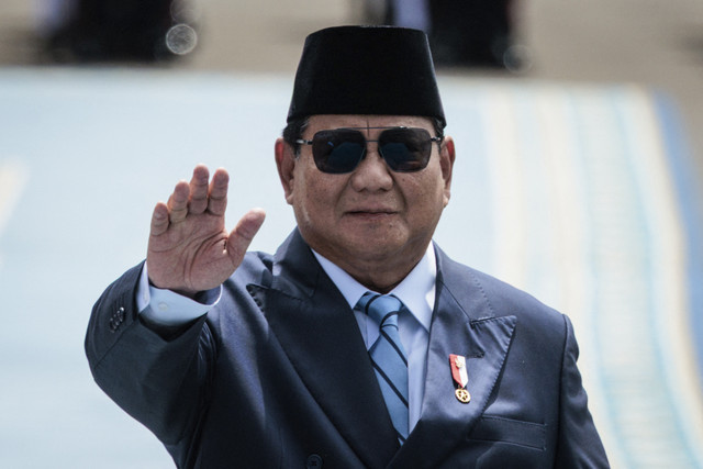 Presiden Prabowo Subianto melambaikan tangan saat berjalan bersama Presiden Brazil Luiz Inacio Lula da Silva untuk pemeriksaan pasukan di Istana Merdeka, Jakarta, Kamis (23/10/2025). Foto: Yasuyoshi Chiba/AFP