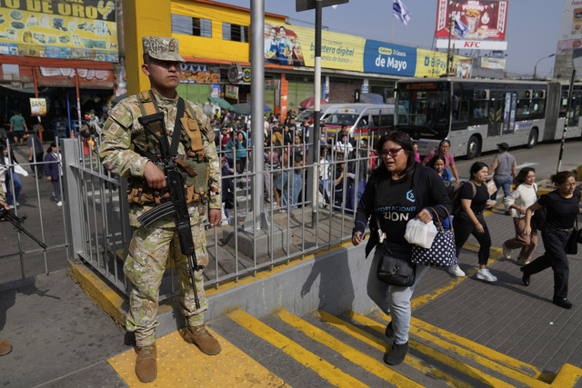 Pejalan kaki melintas di depan tentara yang berjaga di Lima, Peru, Rabu (22/10/2025). Foto: Martin Mejia/AP PHOTO