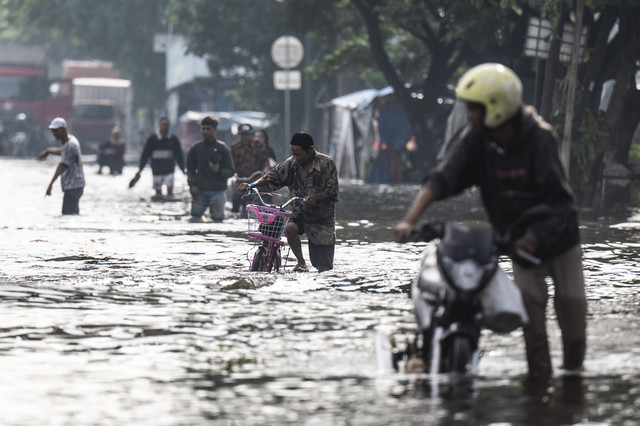 Sejumlah warga berjalan menembus banjir yang menggenangi jalur utama pantura Semarang-Surabaya di Jalan Kaligawe Raya, Semarang, Jawa Tengah, Jumat (24/10/2025). Foto: Aprillio Akbar/ANTARA FOTO